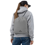 Smoke grey lightweight drawstring bag with Gymplode dual mark imprint worn as backpack by female model